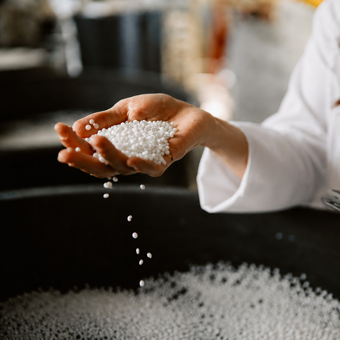 Hand holding white polymer granules