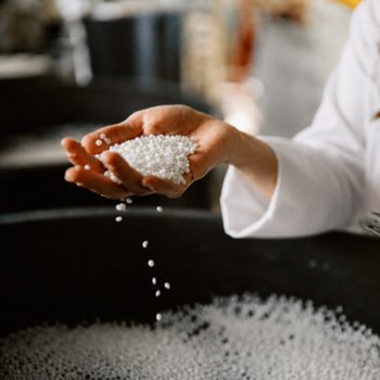 Hand holding white polymer granules